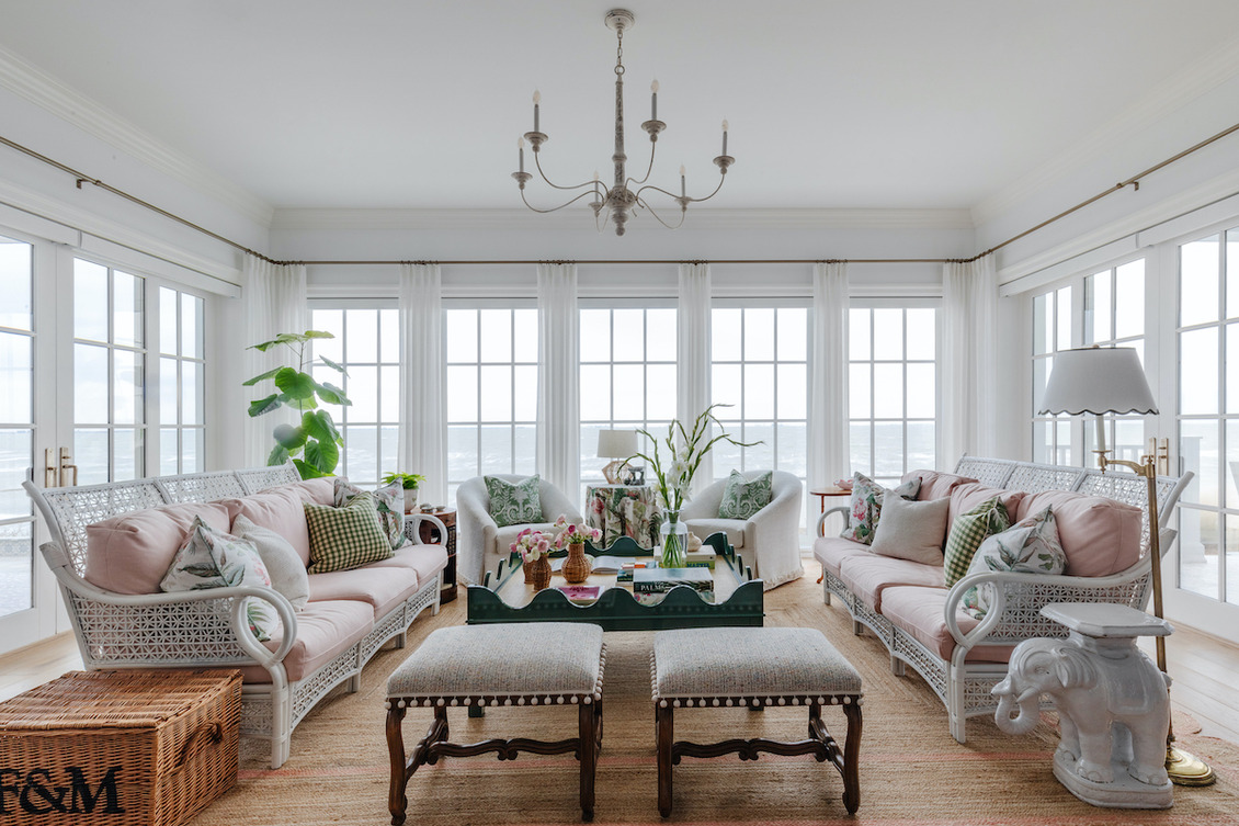 ​A Coastal Grandma Style Home porch featuring upholstered armchairs, rattan benches, wooden center tables, and stools.