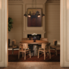 Elegant dining room setup with Arthur Dining Chairs surrounding Henry a round wooden dining table, framed by warm interior lighting, a fireplace, and hanging the essen suspesion lamp.