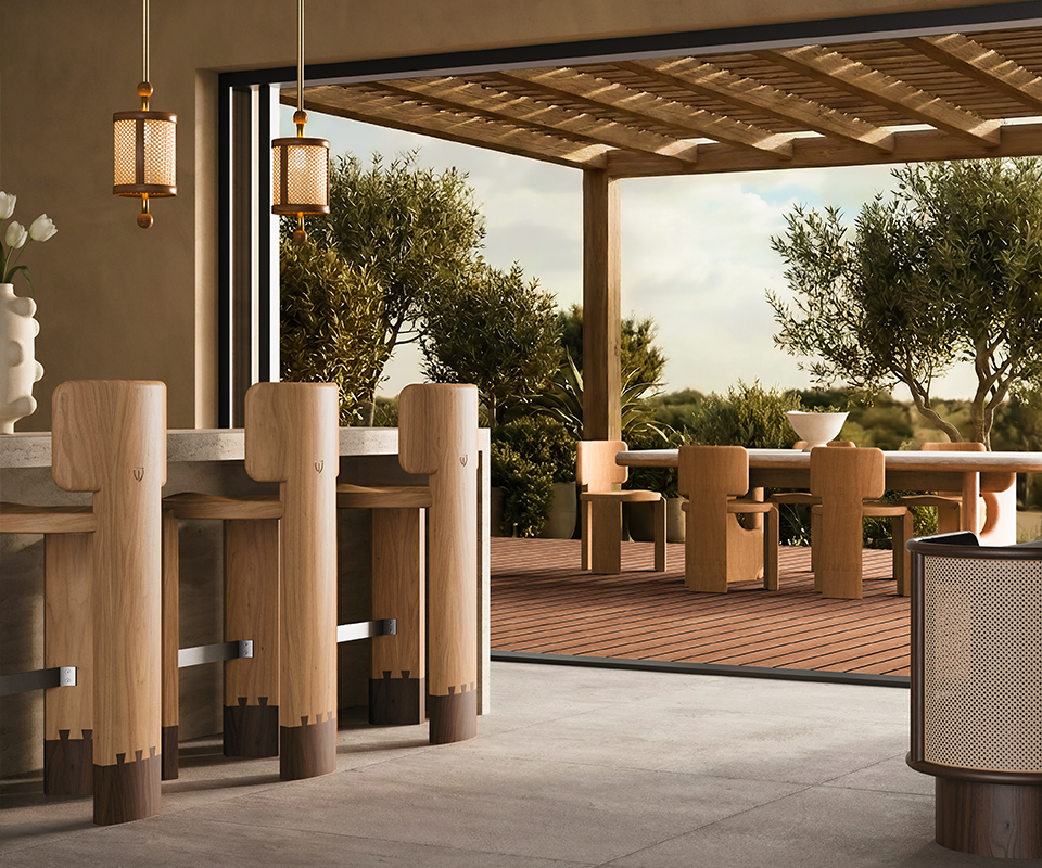 Modern luxury outdoor patio dining area featuring the Benjamin Dining Chair and Portman Dining Table on a wooden deck. Inside, three wooden Benjamin Bar Chairs sit at a stone bar counter under Hamilton Pendant Lamps. A Wodehouse Sideboard decorated with a Hamilton Table Lamp completes the warm, minimalist indoor-outdoor setting.