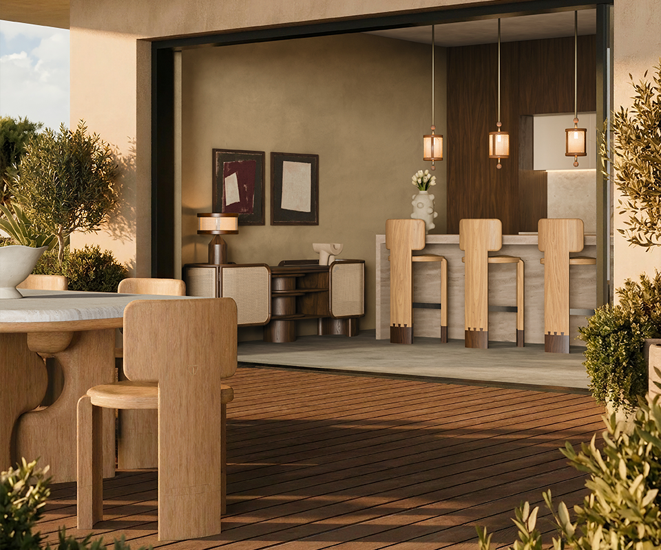 Close-up of three wooden Benjamin Bar Chairs with distinctive dark wood base details lined up at a stone bar counter, illuminated by two hanging Hamilton Pendant Lamps. Through the open sliding doors, the outdoor terrace shows the Portman Dining Table paired with Benjamin Dining Chairs under a wooden pergola.