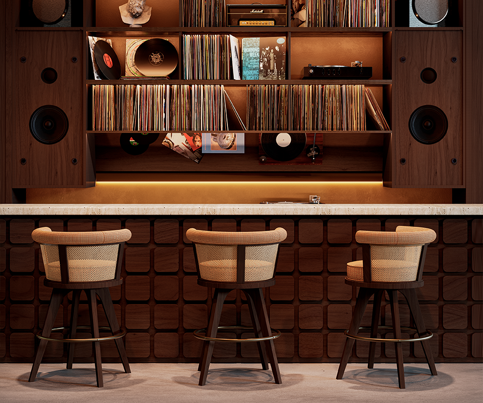 George Bar Chair Three George Bar Chairs by Wood Tailors Club arranged in front of a mid-century modern home listening bar. The chairs feature dark walnut wood legs, a circular brass footrest, and a curved backrest with woven rattan detailing and beige upholstery. The background showcases a sophisticated wooden built-in shelving unit filled with vinyl records, large integrated speakers, and warm ambient lighting.