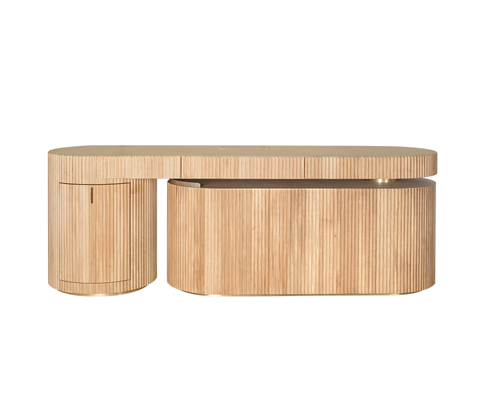 Gifford Desk Gifford desk by Wood Tailors Club in oak. Front view of the desk in a linear, closed configuration. The lower oak shelf module is retracted parallel to the main desktop, with its curved, closed fluted side facing forward on the right, adjacent to the fluted oak cabinet on the far left. Brass leg details are visible.