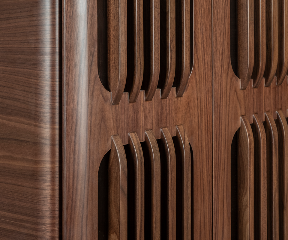 Kennedy Golf Locker A macro detail shot focusing on the craftsmanship of the slatted door panels in smoked walnut wood, showcasing the smooth joinery where the vertical slats meet the solid wood frame.