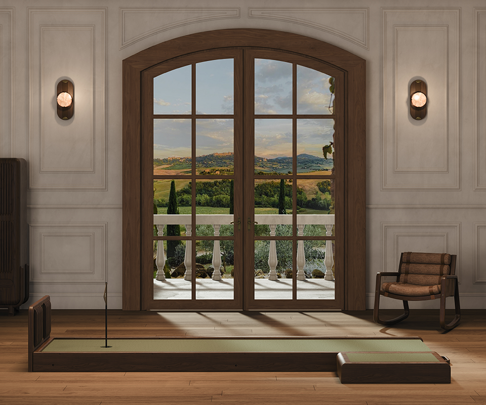 Sutherland Mini Golf set by Wood Tailors Club, crafted in walnut and leather, positioned in a sophisticated interior with a view of a rolling landscape through large arched doors.