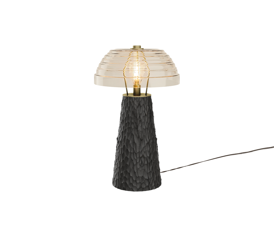 A studio shot of the Lloyd I Table Lamp showcasing a stark black hammered wood base, contrasting beautifully with the warm glow of the bulb under its extra clear ribbed glass shade.