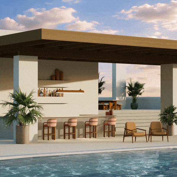 A luxurious outdoor poolside lounge featuring handcrafted teak wood furniture by Wood Tailors Club. In the foreground, two Adam armchairs with tan upholstery sit beside a sparkling blue pool. Behind them, a fluted bar is lined with four James bar chairs featuring pink curved backrests. Above the bar hangs the sleek, linear Bruce suspension lamp. In the background, the Portman dining set is visible on a raised terrace under a modern pergola, all set against a serene sunset sky and tropical greenery.