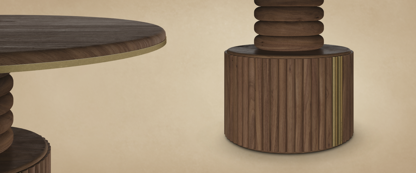Close-up detail of the Stuart I Dining Table by Wood Tailors Club showing the round wooden tabletop with aged brushed brass edge trim and the sculptured solid wood pedestal base with stacked ring contours and vertical fluted grooves.