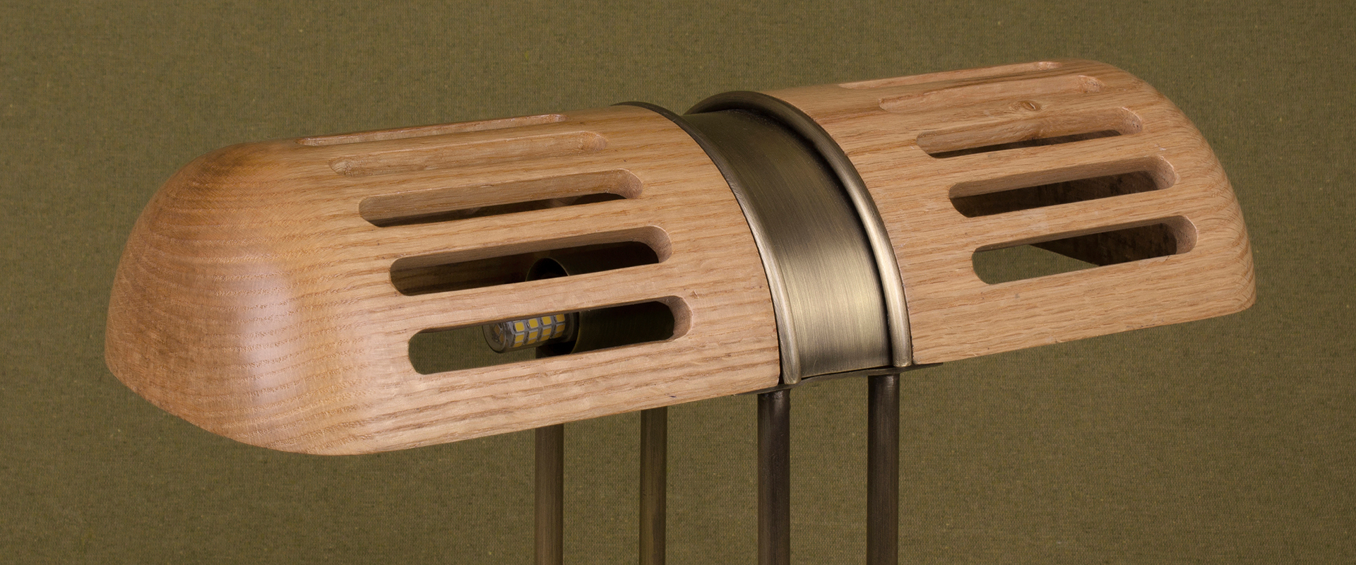 Detail of the Turing Table Lamp shade, crafted in natural oak and aged brushed brass, set against a green background.